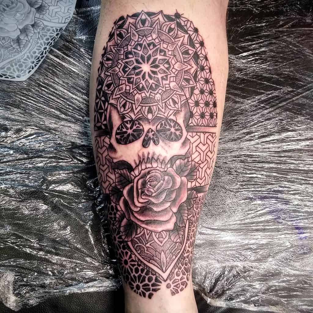 Leg sleeve tattoo of a skull with intricate geometric patterns and a rose 