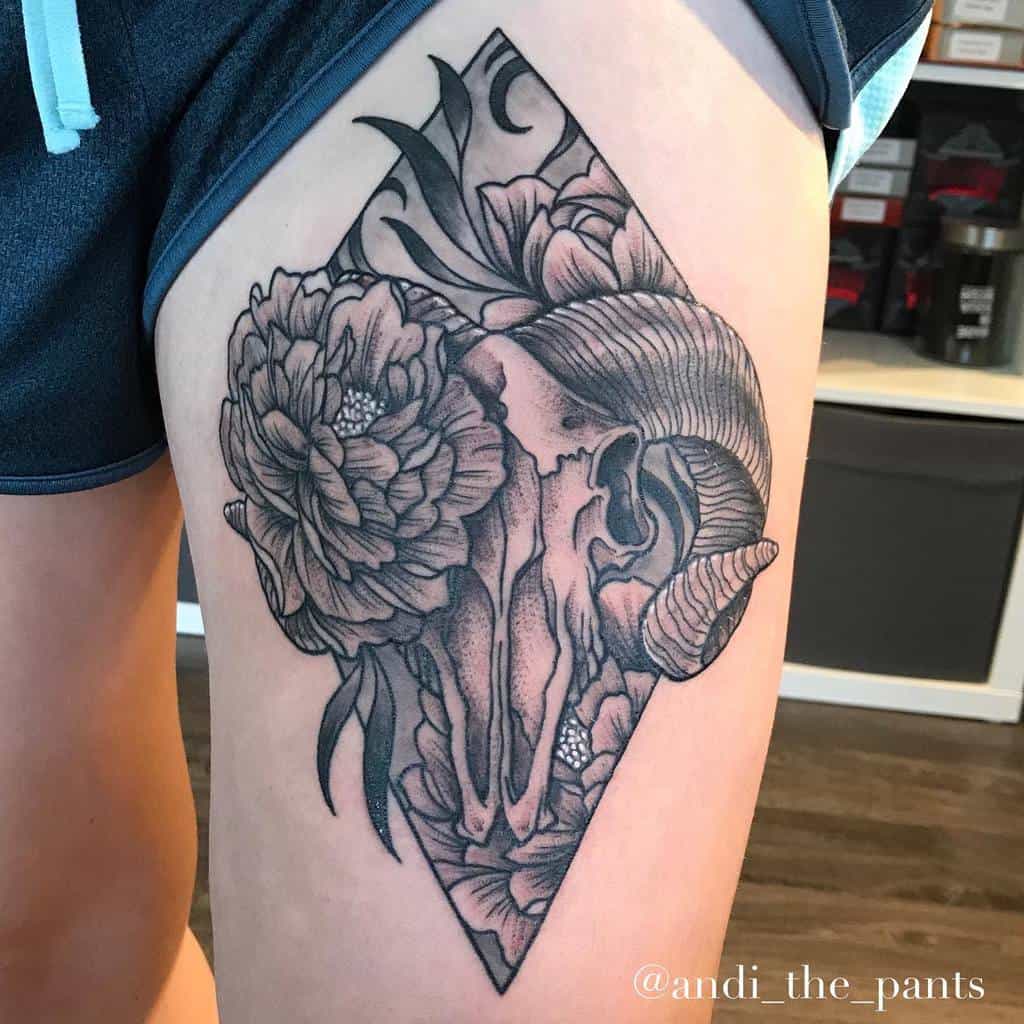 Tattoo of a ram skull adorned with flowers in a striking geometric design on the upper thigh