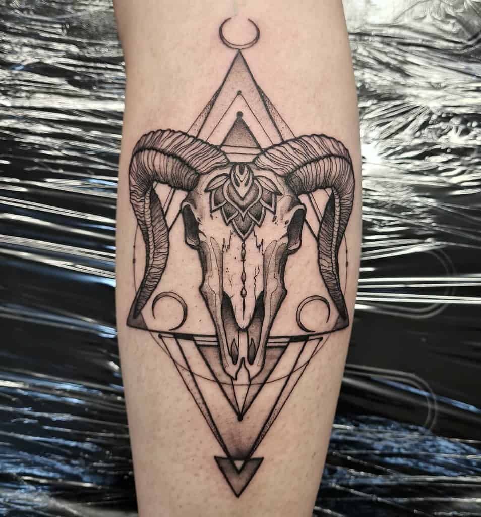 Forearm tattoo featuring a geometric ram skull design with intricate patterns and a crescent moon symbol above