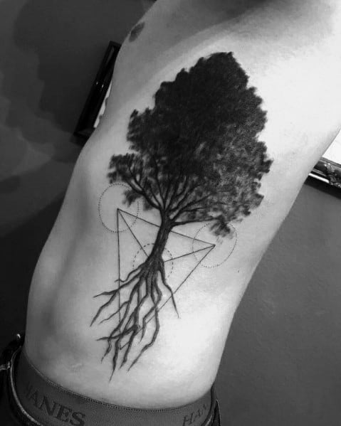 Black and grey rib tattoo of a detailed tree with deep roots, geometric elements, and dotwork, symbolizing balance, growth, and connection to nature.
