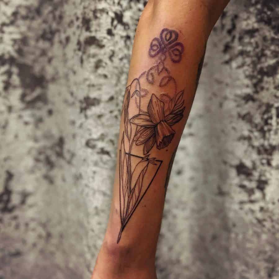 A unique tattoo featuring a daffodil inside a geometric triangle, complemented by an abstract purple design above the flower, blending linear and colorful elements.