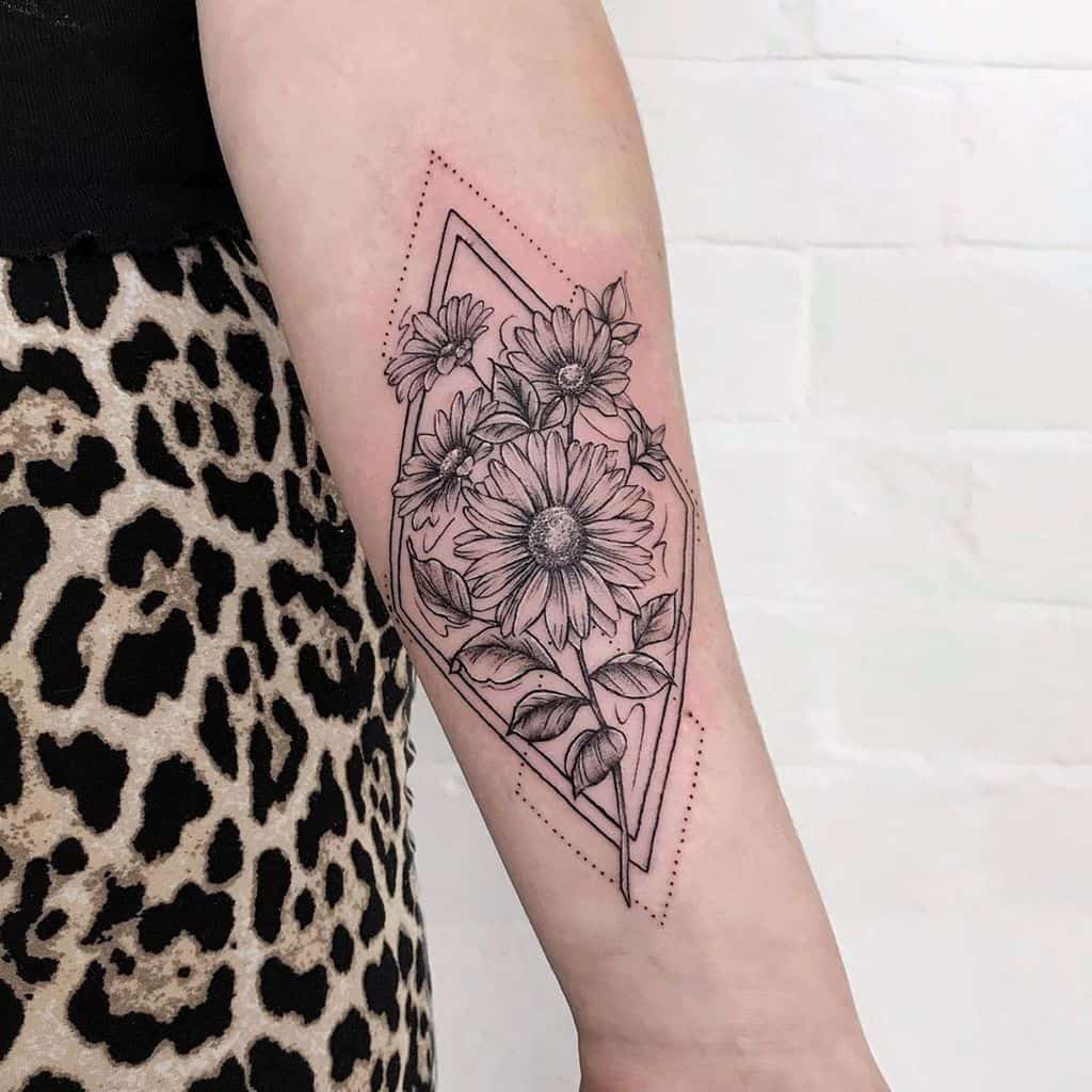 Forearm tattoo black and grey shading geometric shapes framing daisies