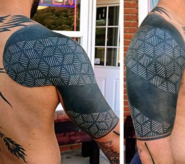 Geometric black shoulder tattoo with intricate white patterns on a man’s arm