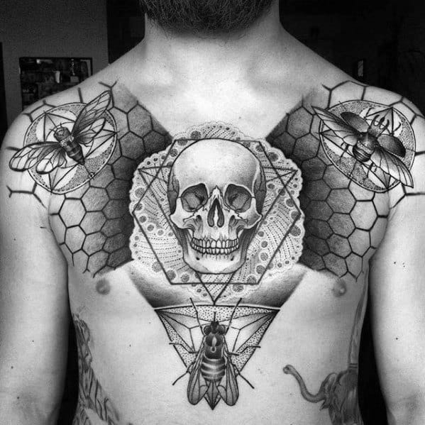 Geometric chest tattoo featuring a central skull with detailed flies, honeycomb patterns, and dotwork textures for a bold symmetrical design.