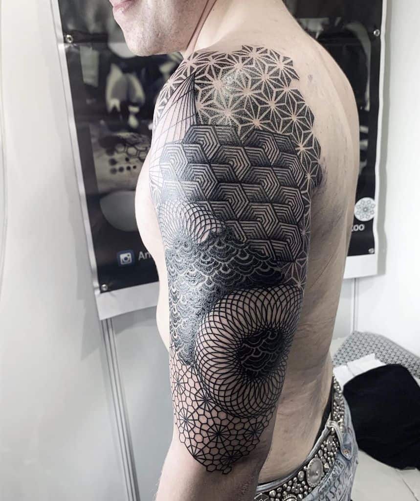 A man with a detailed geometric tattoo sleeve on his arm, featuring intricate patterns and shapes