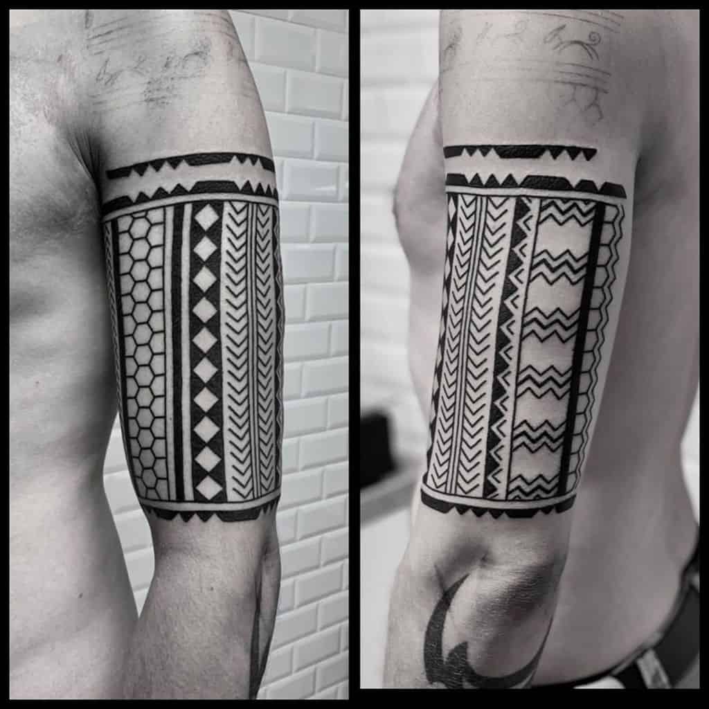 Black geometric tattoo bands on a man's upper arm with zigzags, triangles, and hexagons