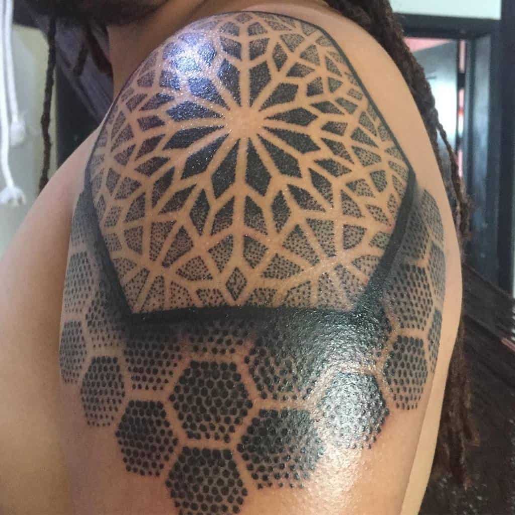 Geometric tattoo on a man's shoulder with intricate patterns and hexagonal shapes