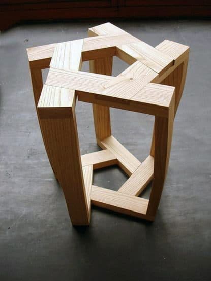 Wooden geometric sculpture with interlocking rectangular frames on a dark surface