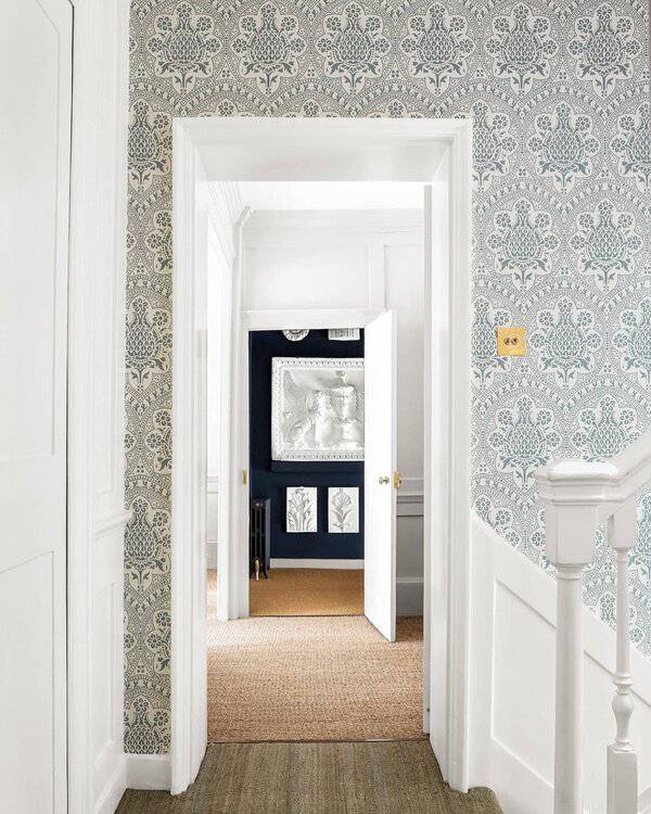 Bold tub with overhead shower rail, grey panelled walls, and subtle green wallpaper for a stylish heritage-meets-modern bathroom.