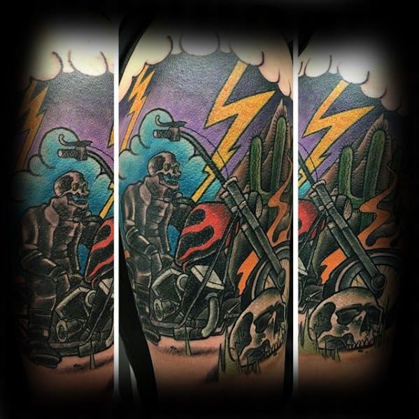 Colorful Ghost Rider tattoo with a cartoon-style skeleton rider, flaming bike, desert scene, cacti, skulls, and lightning bolts.