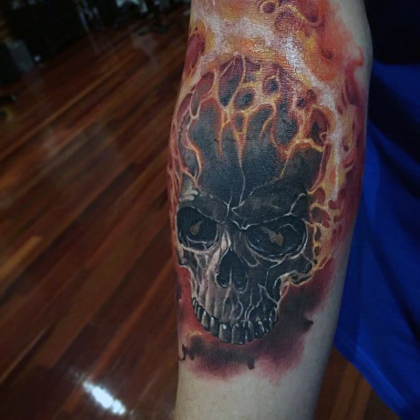 Ghost Rider forearm tattoo featuring a blackened skull engulfed in realistic orange flames with glowing highlights and dark shadows.