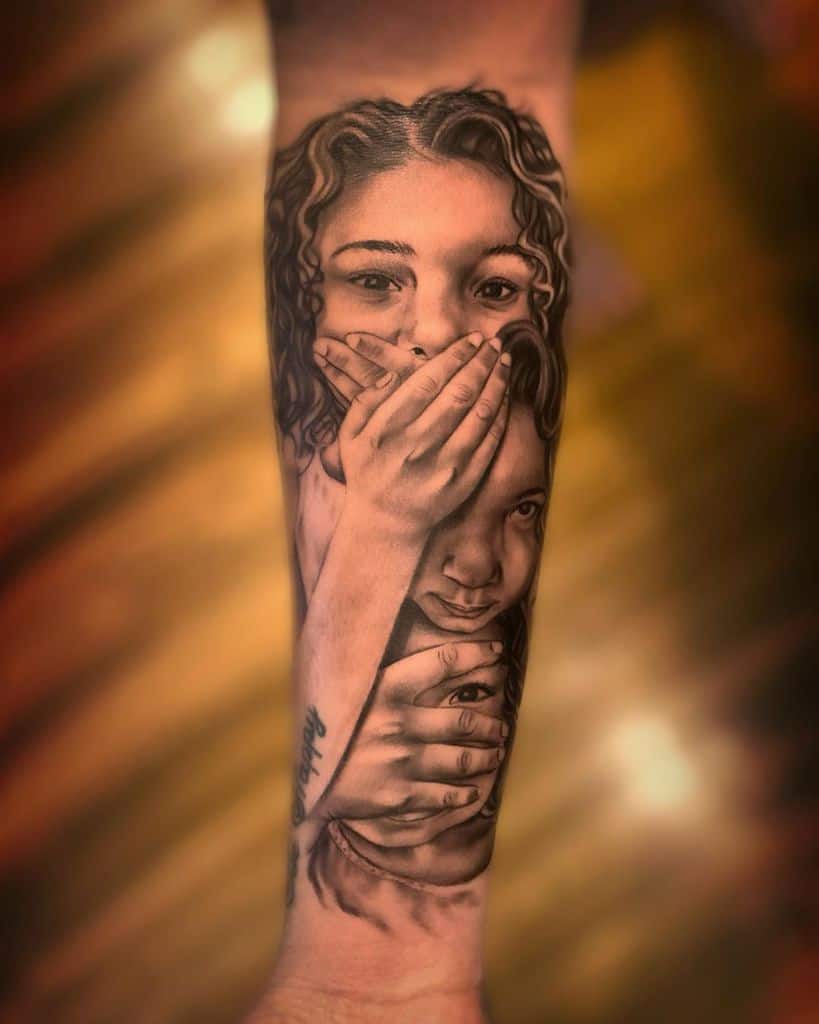 Realistic tattoo of two faces on a forearm, with hands covering the mouth and eyes, symbolizing 'Speak No Evil' and 'See No Evil' in detailed shading