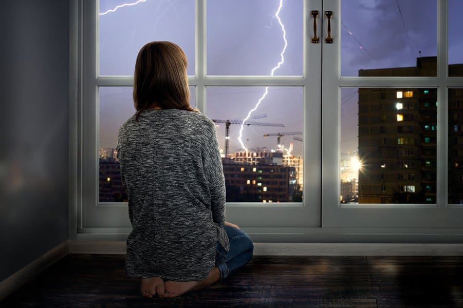 girl looks through the window at the lightning