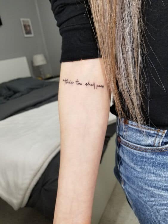 "This too shall pass" tattoo in a simple font on the forearm.