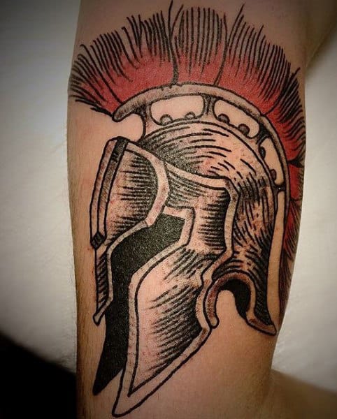 Tattoo of a Spartan helmet with a red plume, embodying the fierce spirit of a gladiator, proudly displayed on someone's forearm