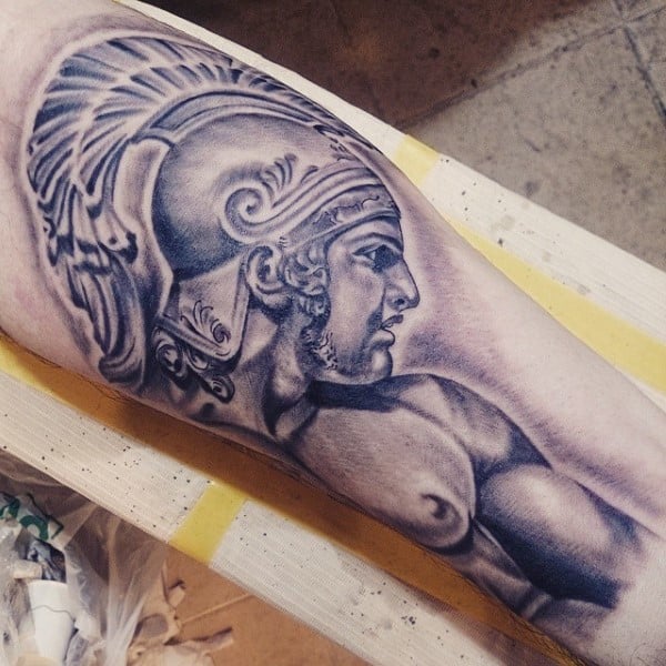 Tattoo of an ancient gladiator warrior wearing a helmet, detailed in black and grey, on an arm