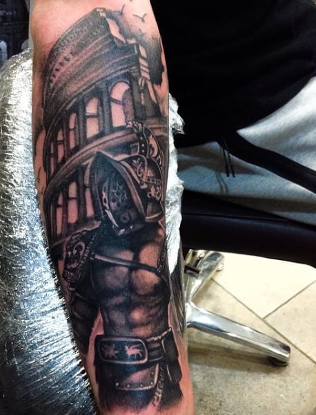 Arm tattoo of a Roman gladiator helmet and the Colosseum in black and gray shading capturing the fierce spirit of the ancient gladiators