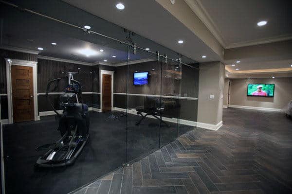 Home gym with exercise bike in a glass-walled room; TV on exterior wall displaying a sports scene; perfect for home workouts