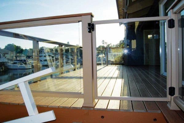 Sunny terrace with glass railing and gated deck overlooking a marina with docked boats