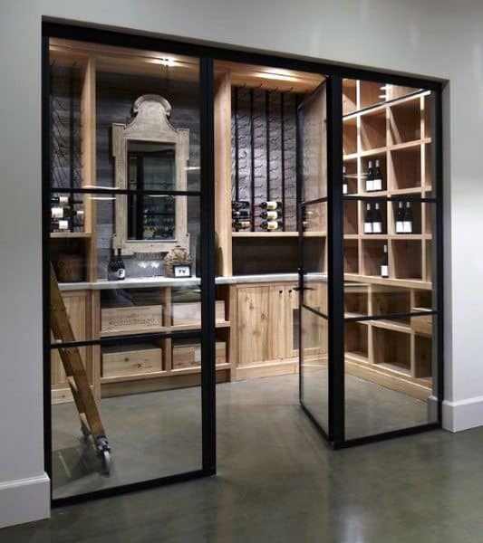 Modern wine cellar with wooden shelves, a sliding glass door, a ladder, and space for an extensive wine collection