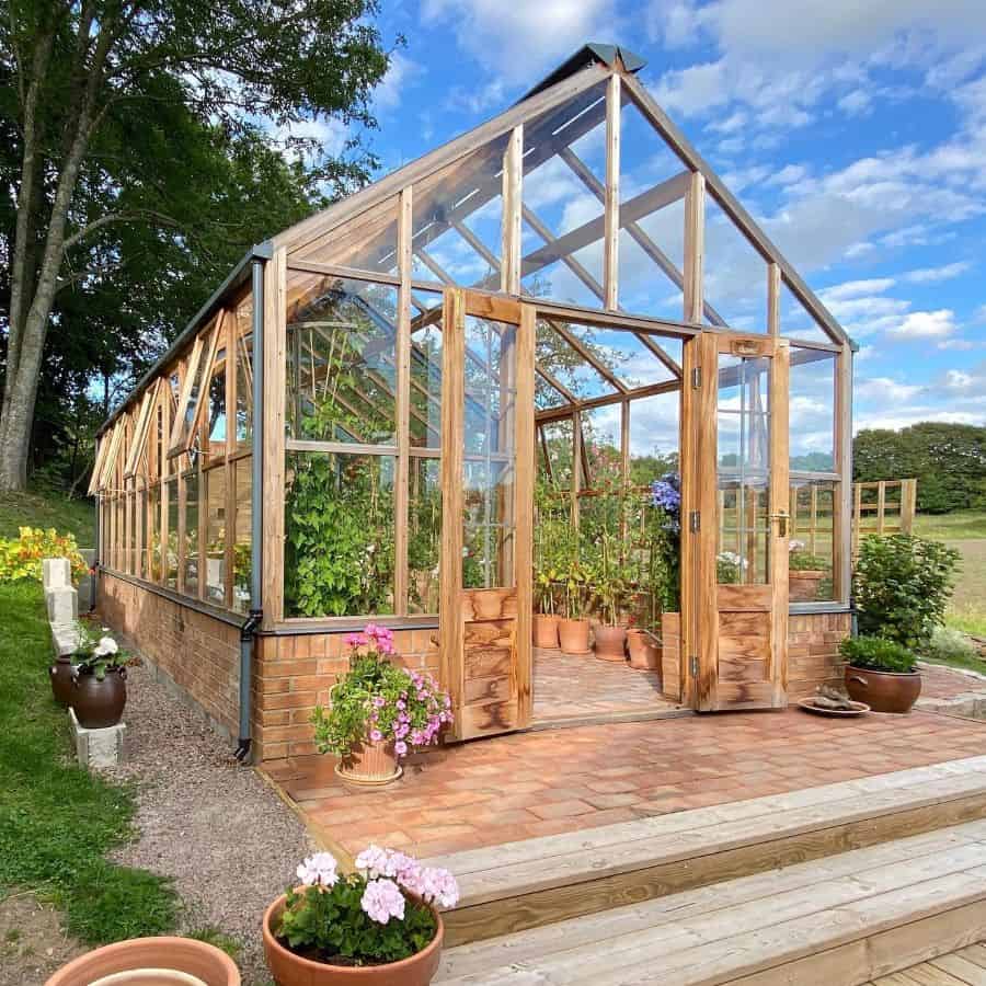 wood frame glass greenhouse terracotta pot plants