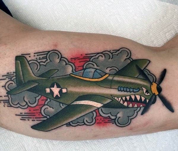 Tattoo of a green airplane with an angry face flying through clouds