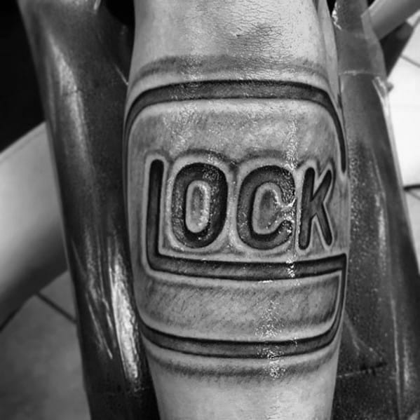 Black and grey tattoo of the Glock logo on the forearm, featuring bold lettering and shading for a three-dimensional, embossed effect.