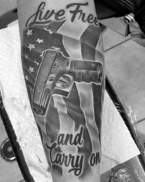 Black and grey tattoo featuring a Glock pistol, an American flag, and the phrase "Live Free and Carry On," symbolizing patriotism and self-defense.