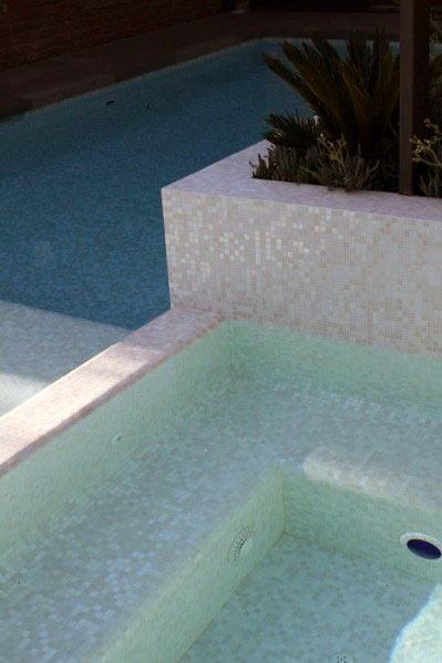 Elegant pool and spa with white and pale green mosaic tiles, featuring a built-in planter.