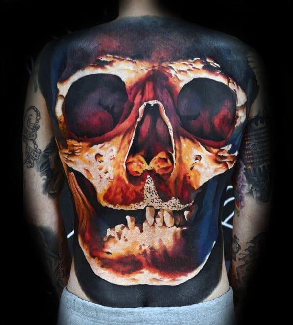 Back tattoo depicting a large, fiery skull with detailed shading and vibrant colors