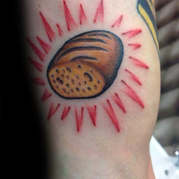 Bold and colorful tattoo of a loaf of bread with red rays radiating around it, giving it a vibrant and dynamic traditional tattoo style.