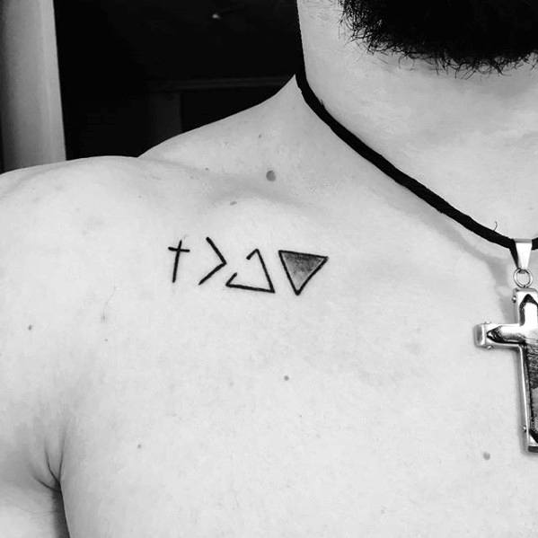 Shoulder tattoo featuring the "God is greater than the highs and lows" symbol with a cross and geometric shapes