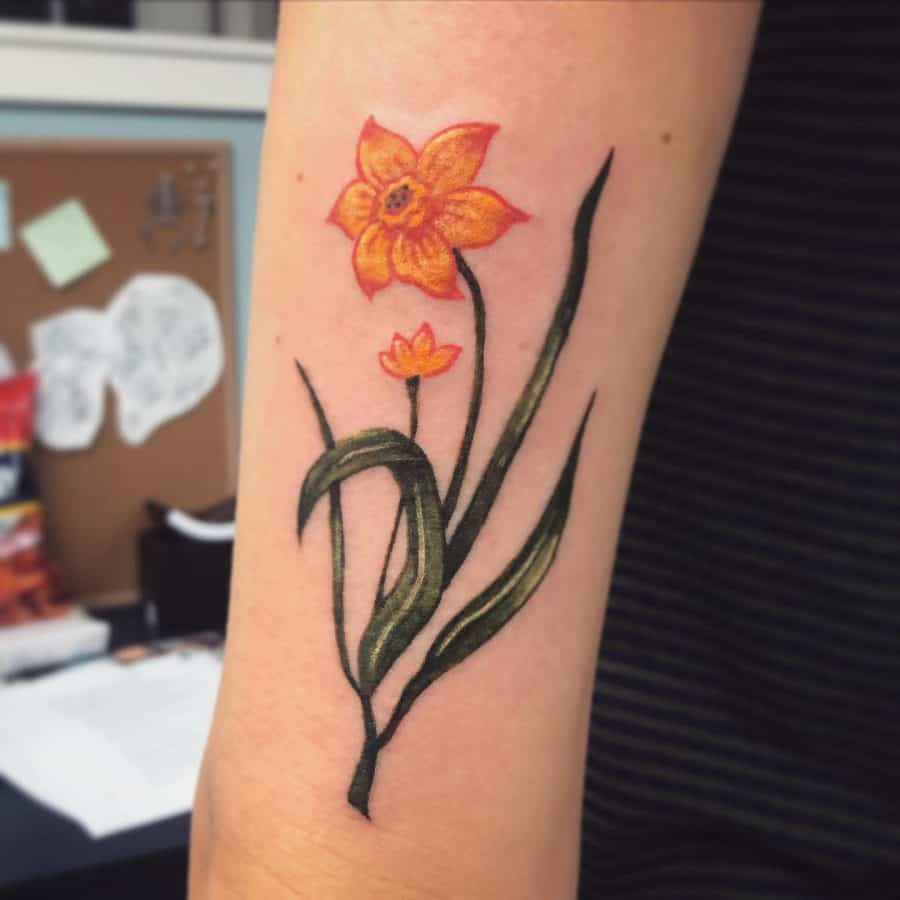 A vibrant tattoo of two daffodils, with bold yellow petals and green leaves, beautifully detailed and standing out against a contrasting background.