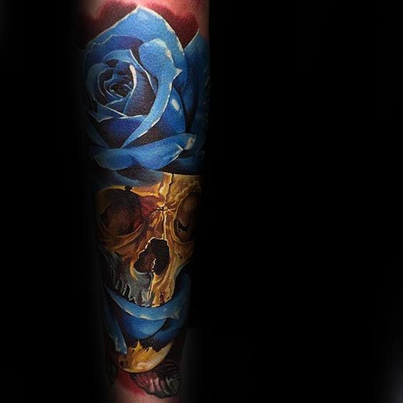 Tattoo of a golden skull surrounded by blue roses 