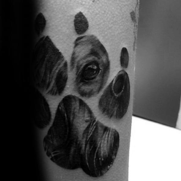 Creative Golden Retriever tattoo featuring a paw print design with a detailed dog portrait subtly blended into the shading for a unique effect.