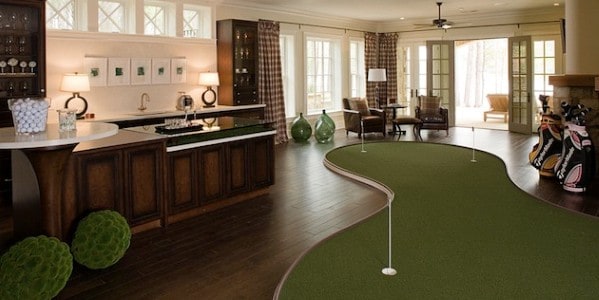 Man cave room with a bar, indoor golf putting green, armchairs, and large windows