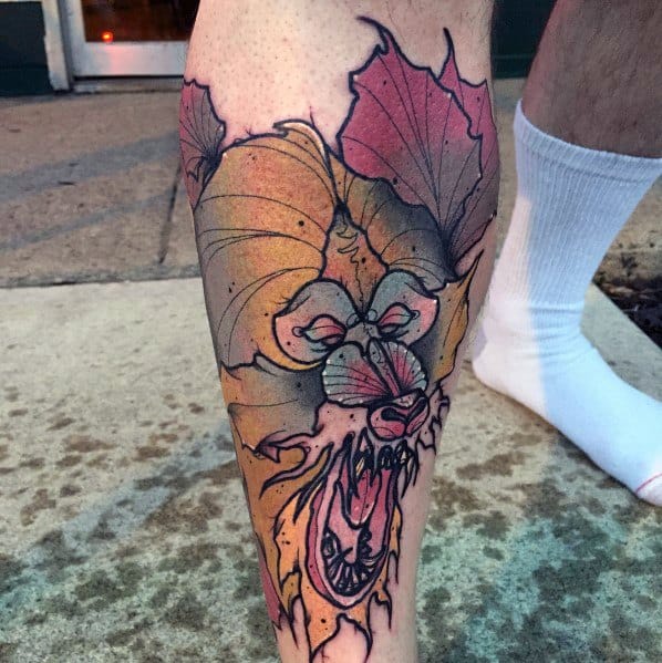 Neo-traditional baboon tattoo with bold outlines, autumn leaves, and a fierce expression, blending warm tones for a striking and dynamic leg design.