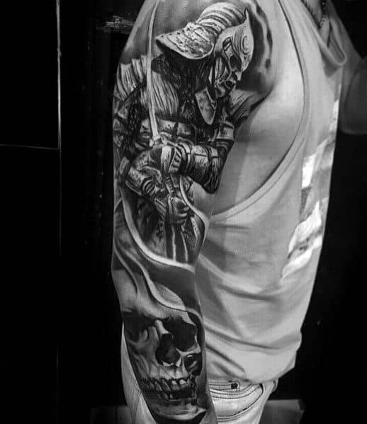 Black and grey full-sleeve tattoo featuring a skeletal samurai warrior wielding a sword, detailed armor, and a large skull for a dark warrior theme.