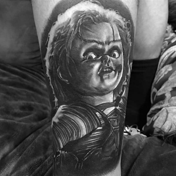 Black and grey Chucky tattoo with dramatic shading, capturing his eerie expression and intense glare for a bold horror-inspired design.