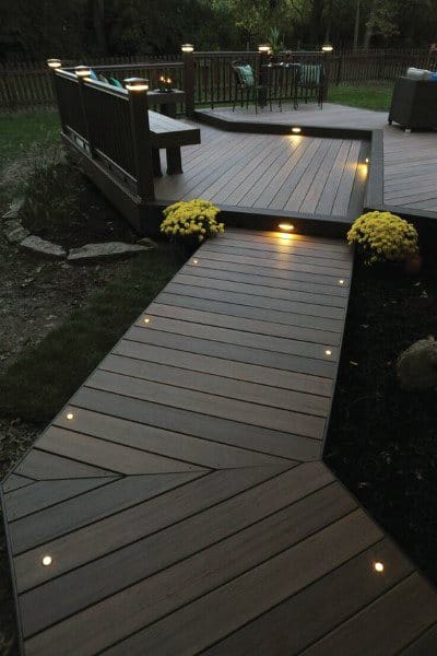 Wooden backyard deck with pathway lighting and railing accents for a warm evening ambiance.