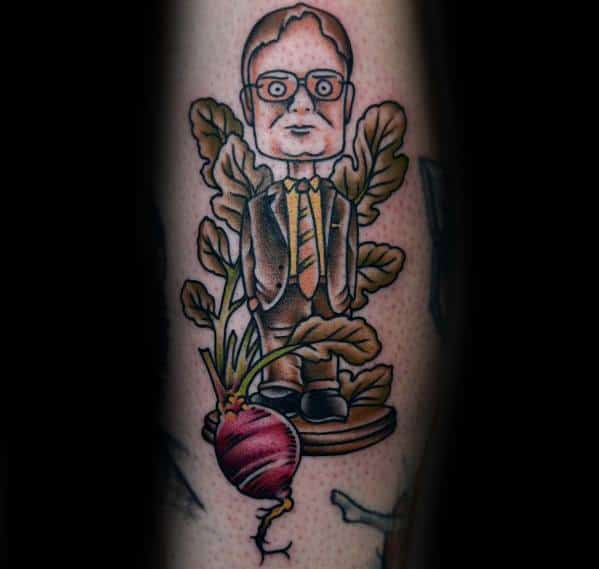 Tattoo of Dwight Schrute as a wooden figurine, standing on a base with beet leaves behind him and a large beet at the bottom, in a cartoon style.