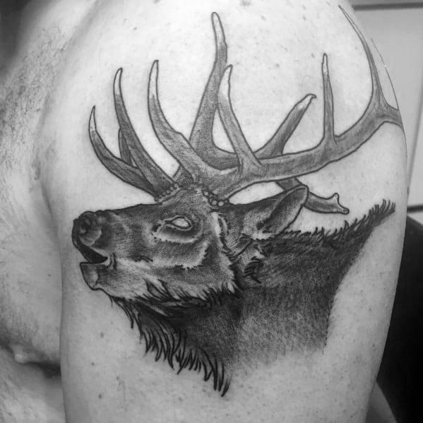 Realistic black and grey elk tattoo on the upper arm, featuring bold antlers, detailed shading, and a lifelike roaring expression.