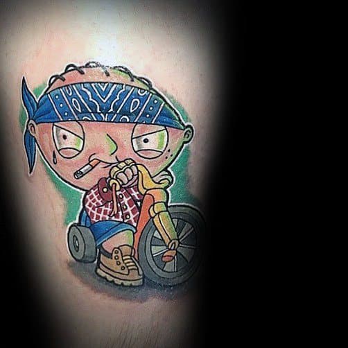 Tattoo of Stewie Griffin from Family Guy dressed as a gangster, wearing a blue bandana, plaid shirt, and boots, riding his tricycle with a cigarette.