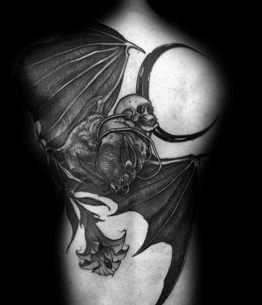 Gothic black and grey back tattoo featuring a detailed bat with outstretched wings, a skull, and a crescent moon for a dark aesthetic.
