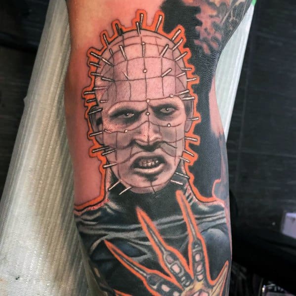 Vibrant *Hellraiser* tattoo of Pinhead with bold outlines, eerie shading, and fiery orange accents for a striking and intense design.