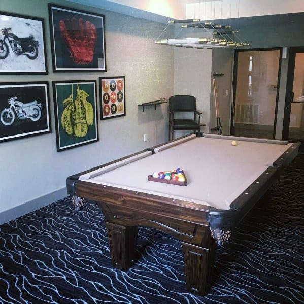 Modern billiard room with art deco wall prints, beige felt table, and patterned flooring.