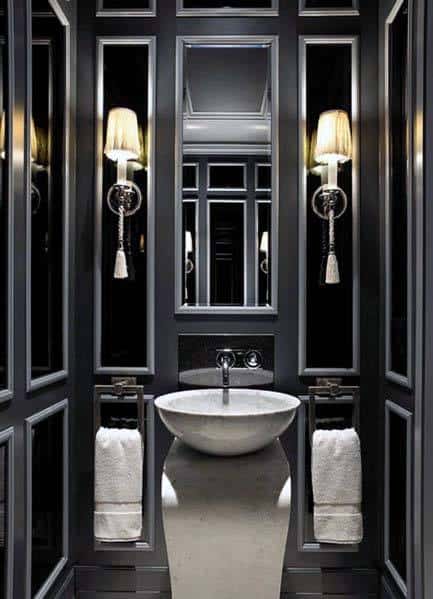 Elegant black bathroom with pedestal sink, framed mirrors, and wall-mounted sconces.