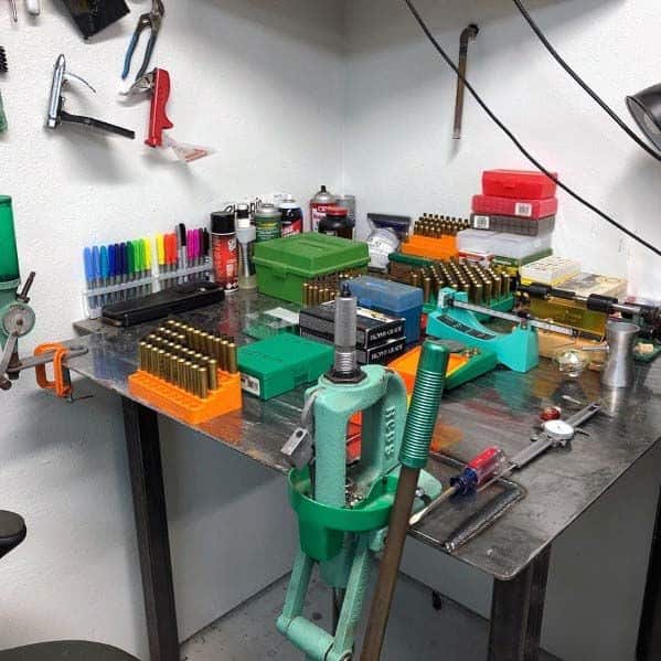 Compact metal reloading bench with a press, organized ammo trays, tools, and colorful markers for efficient workspace use
