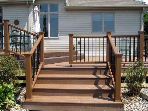 Wooden deck stairs with a black gate railings leading to a house