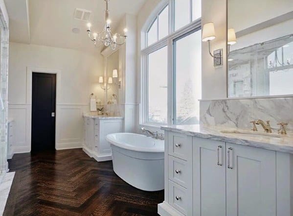 Luxurious bathroom with a freestanding tub, white marble counters, and herringbone wood floor